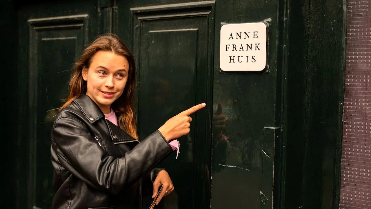A guide pointing at the Anne Frank Huis nameplate beside the museum entrance