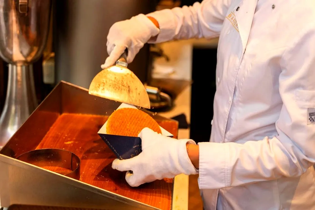 A baker in white gloves cutting a fresh stroopwafel in an Amsterdam bakery