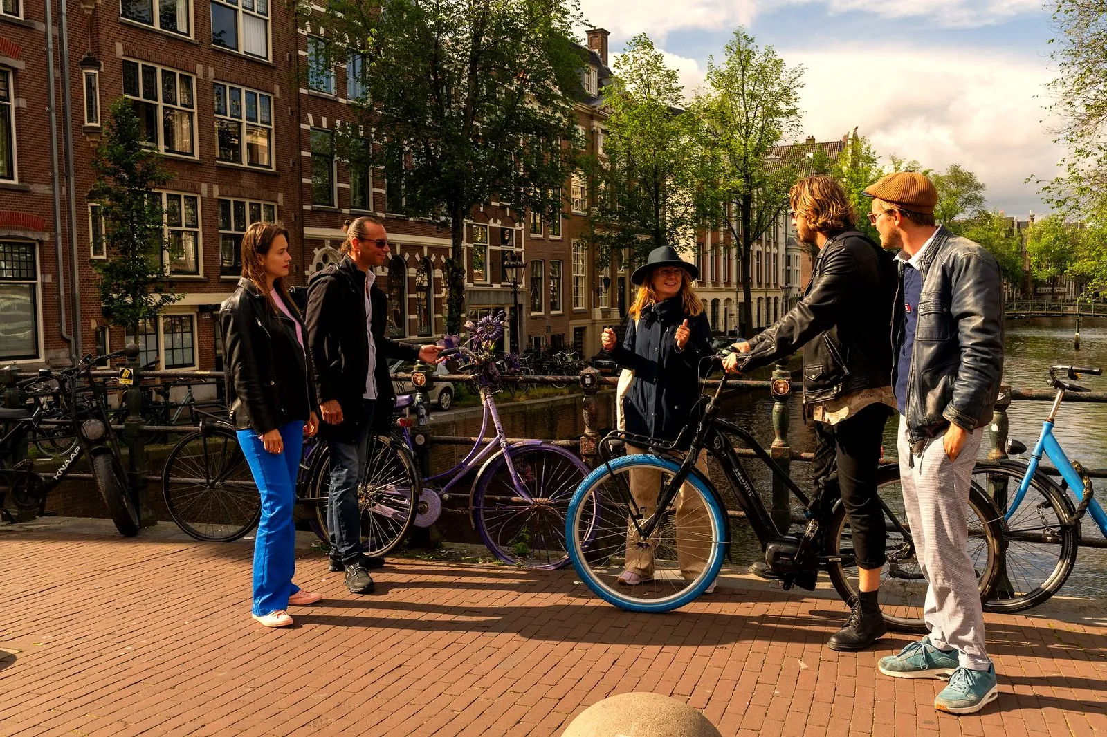 A team posing with bikes on an Amsterdam canal bridge