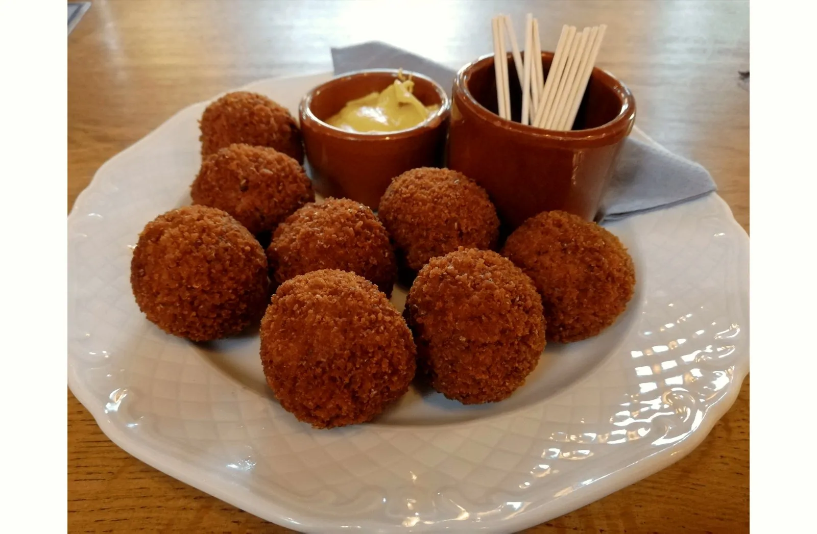 Plate of Dutch bitterballen with mustard and toothpicks in a cafe