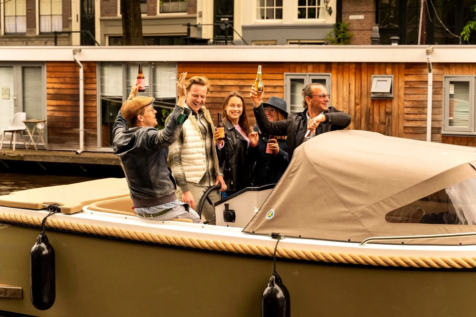 A group raising drinks on a private canal boat at dusk in Amsterdam