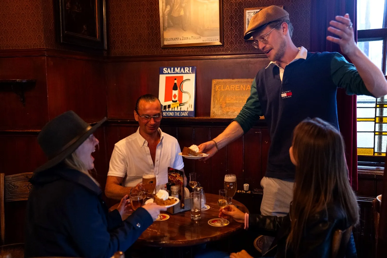 Guide serving snacks to guests at a table in an Amsterdam brown cafe