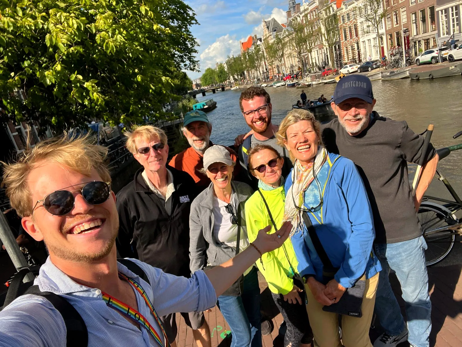 A group of friends taking a selfie on an Amsterdam canal bridge during a food tour