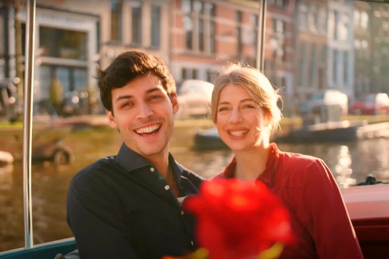 A smiling couple with a red rose on a canal boat in Amsterdam