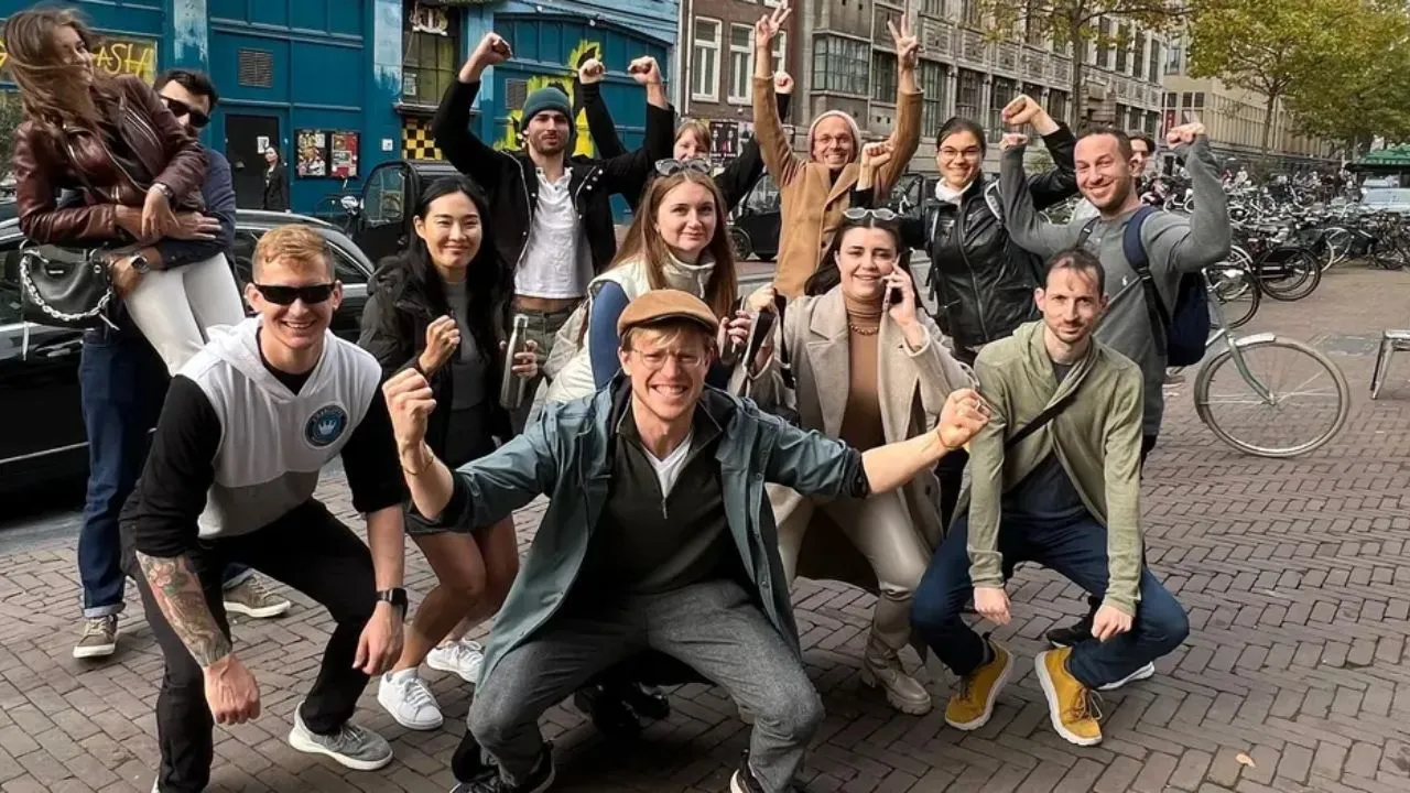 A food tour group cheering with arms raised on an Amsterdam street
