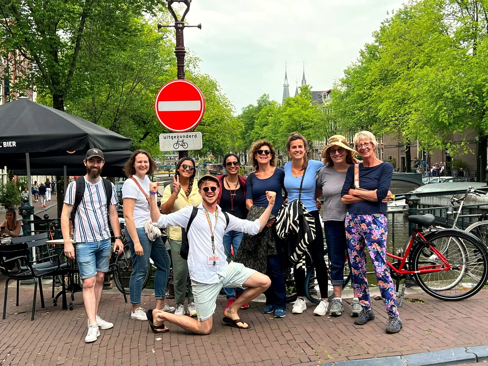 Nine food tour guests bonding with their guide on an Amsterdam canal street