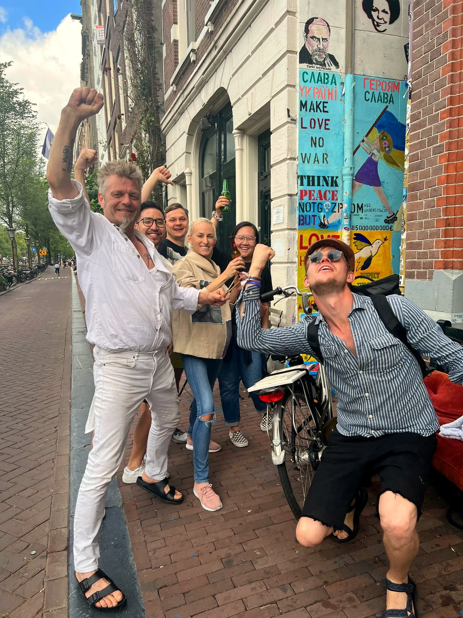 A lively food tour group cheering with raised fists on an Amsterdam street