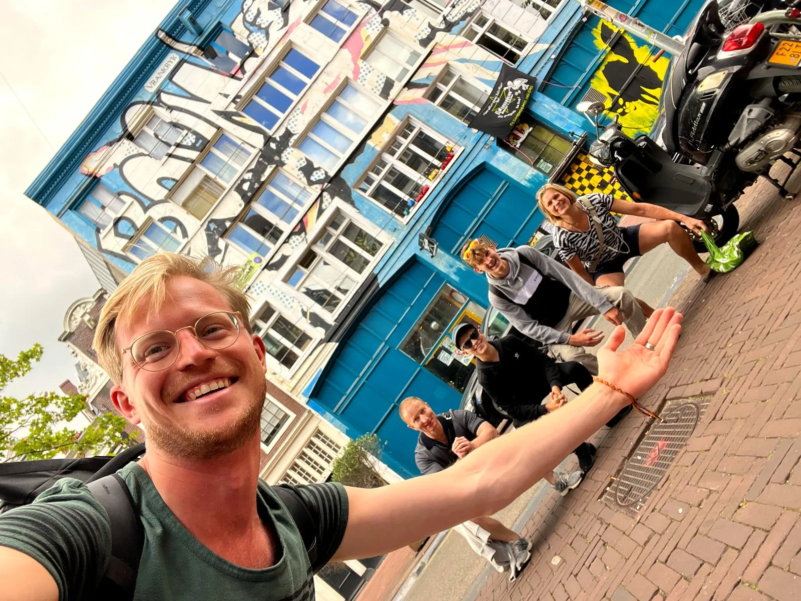 Tour guide taking a selfie with a small group in front of a colourful Amsterdam building