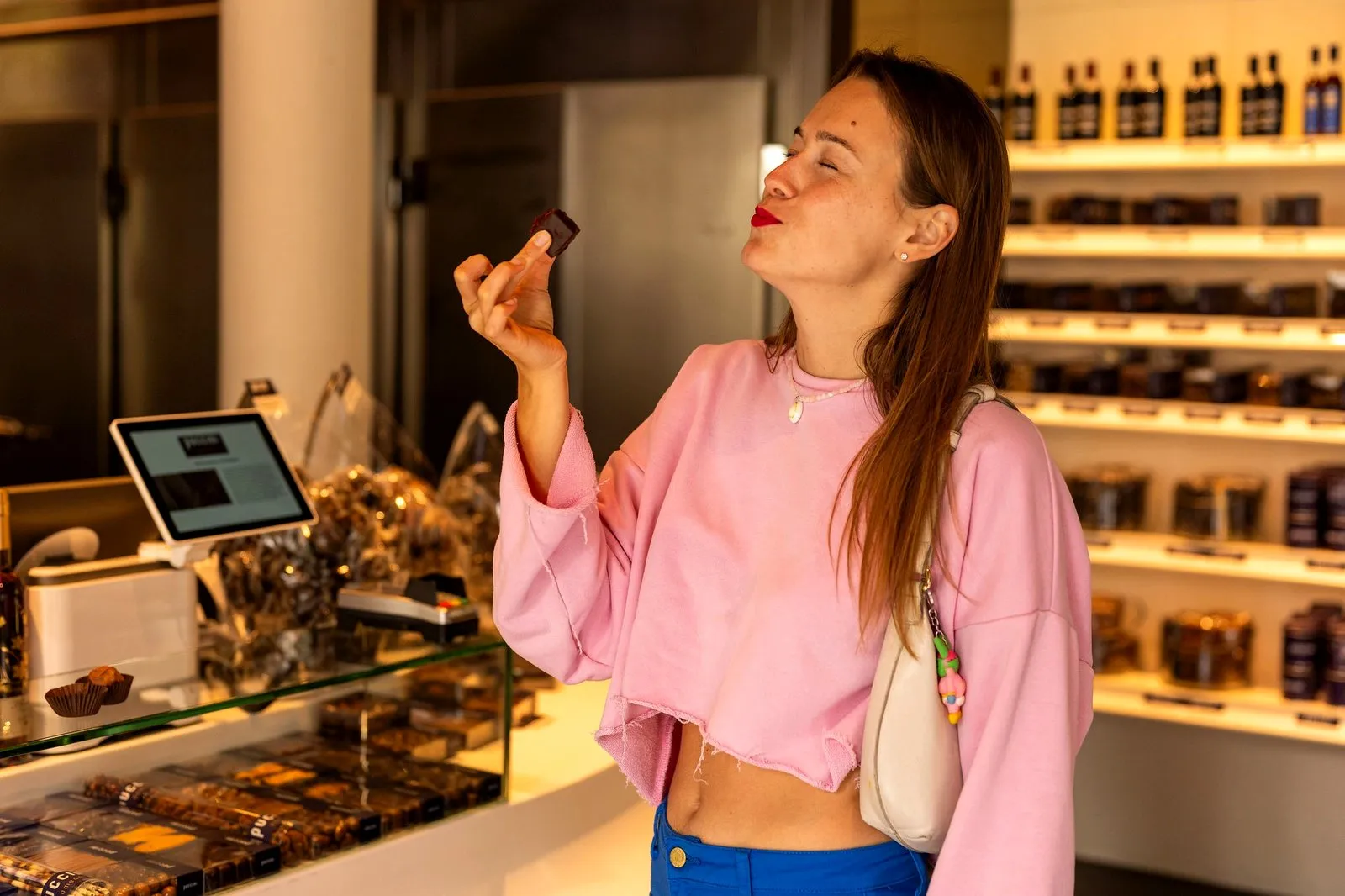 Woman tasting a chocolate with her eyes closed in a chocolate shop