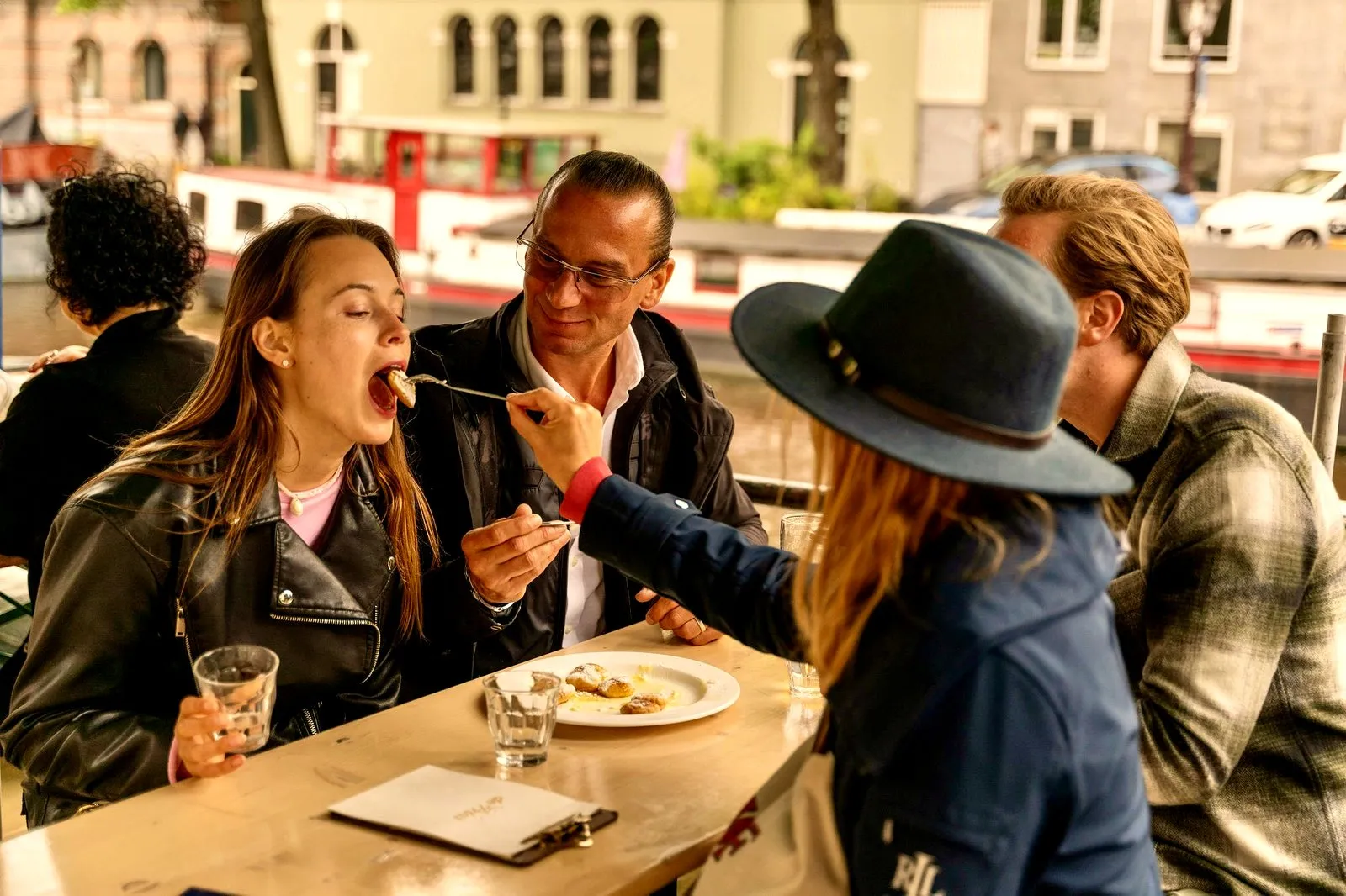 A guest being fed a bite at a canal-side table during an Amsterdam food tour
