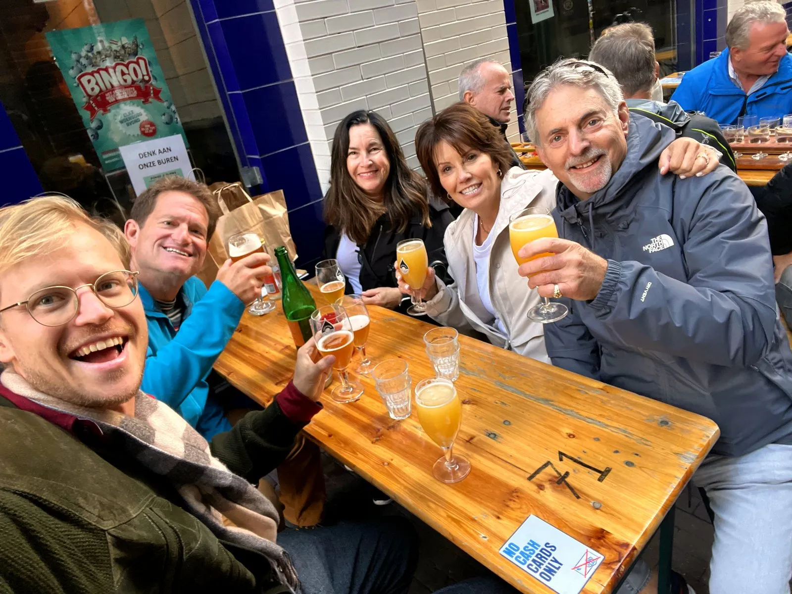 A group toasting beers and mimosas at an outdoor Amsterdam terrace selfie