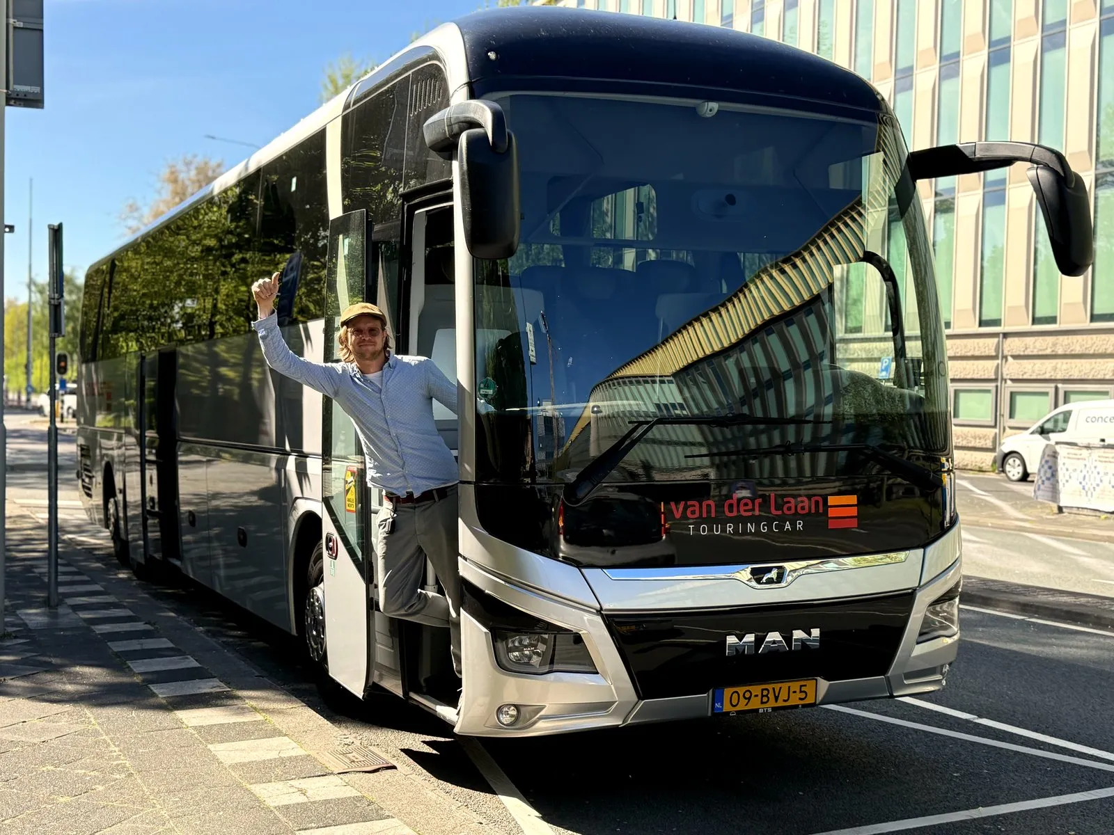 Tour guide waving from the door of a private coach in Amsterdam