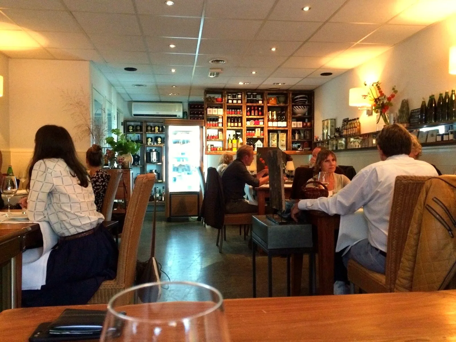 Warm wine bar interior with diners and bottles on the shelves