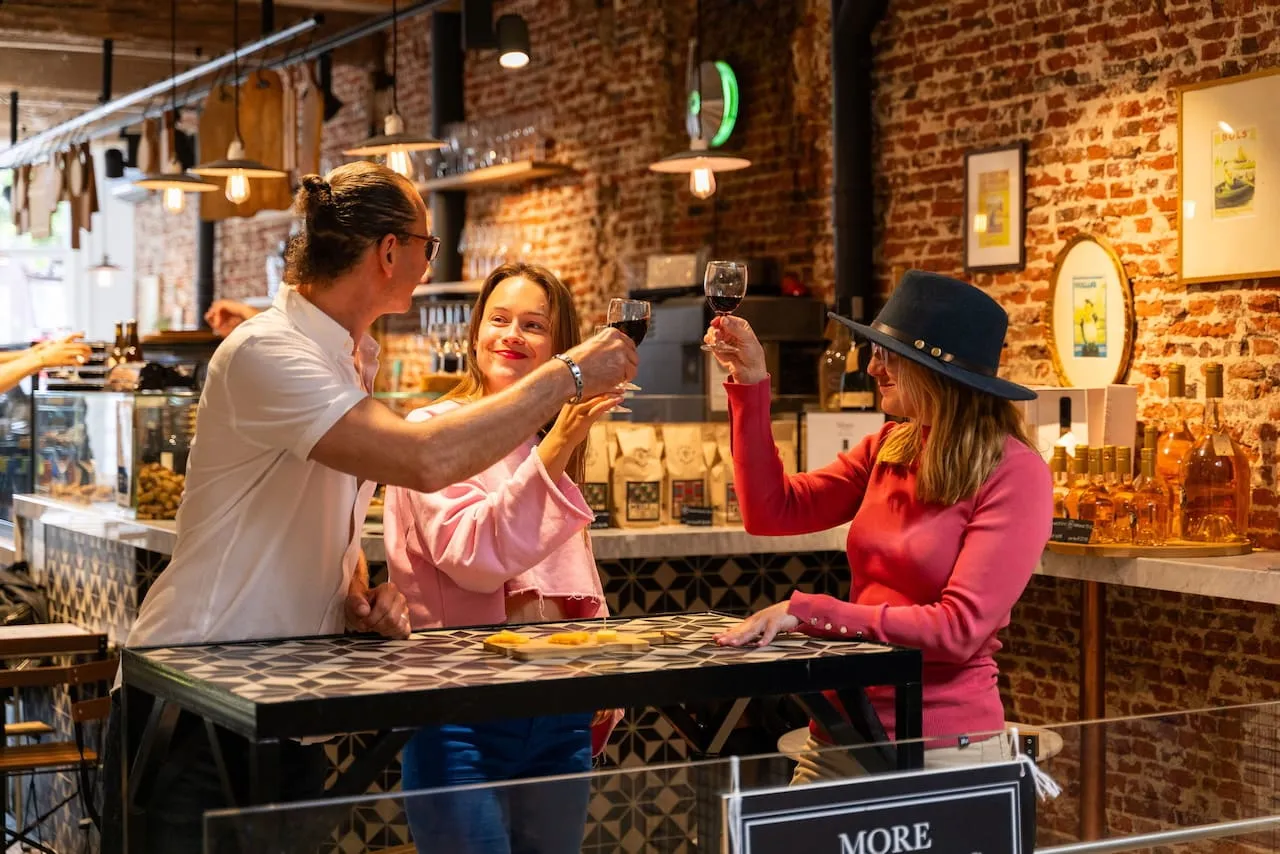 A group toasting glasses of red wine at a brick-walled Amsterdam market bar