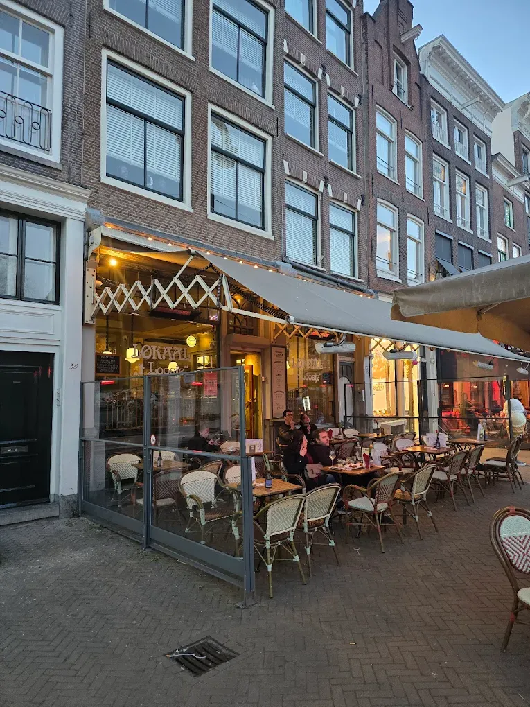 Cafe Loosje terrace in Amsterdam with tables under an awning in the evening