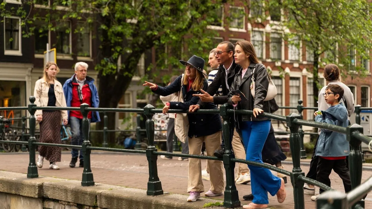 People standing on a bridge enjoying the view and chatting during an Amsterdam tour.