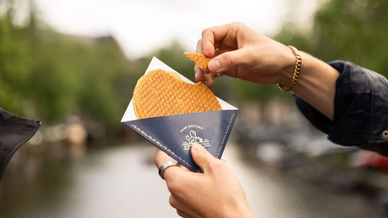 People holding fresh stroopwafels and enjoying them together outdoors