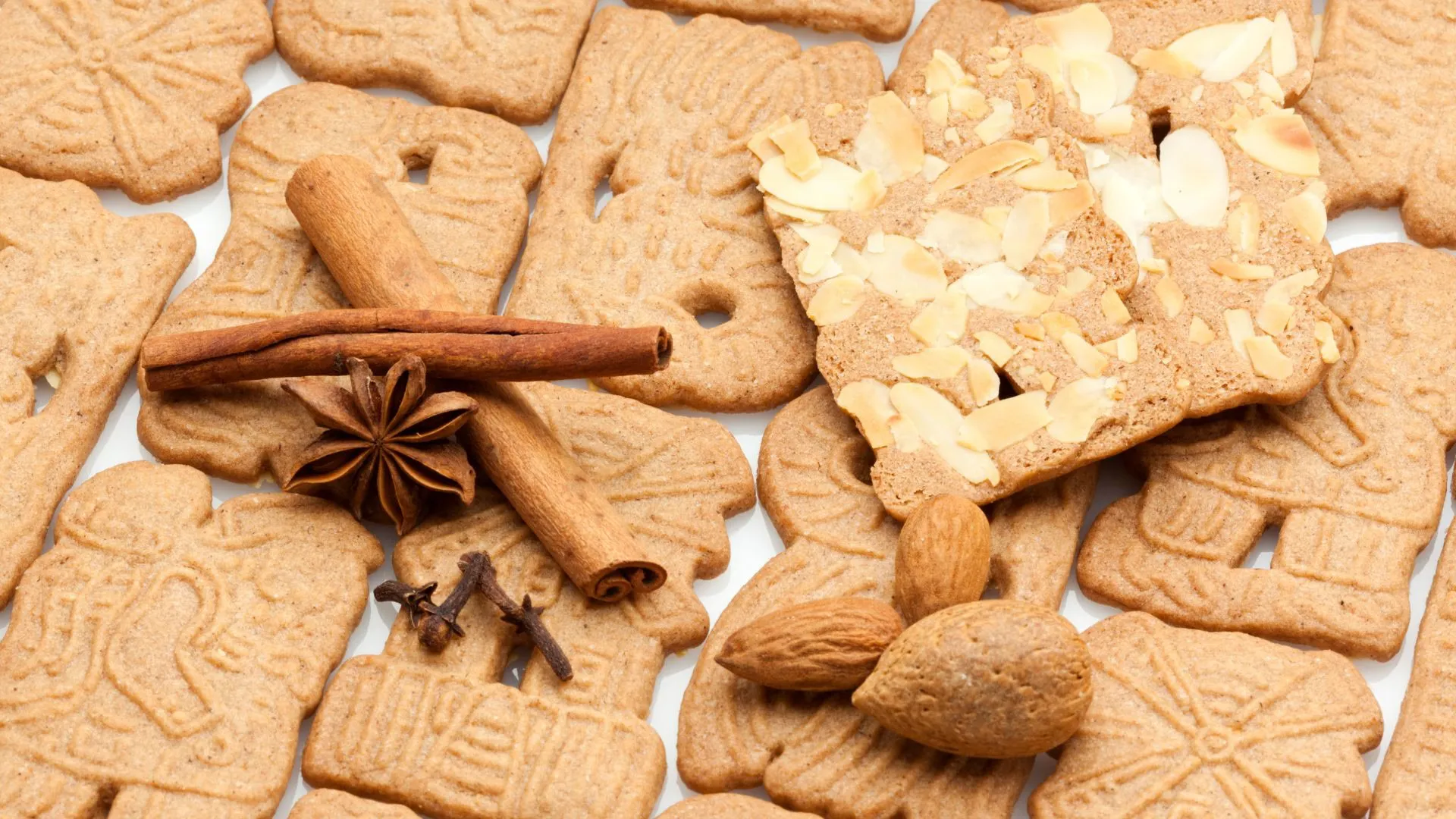 Speculaas cookies with stamped windmill patterns, surrounded by cinnamon sticks, star anise, cloves and almonds